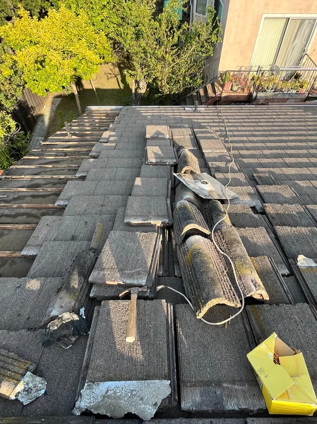 Tile roof repair in progress with tiles lifted along the ridge