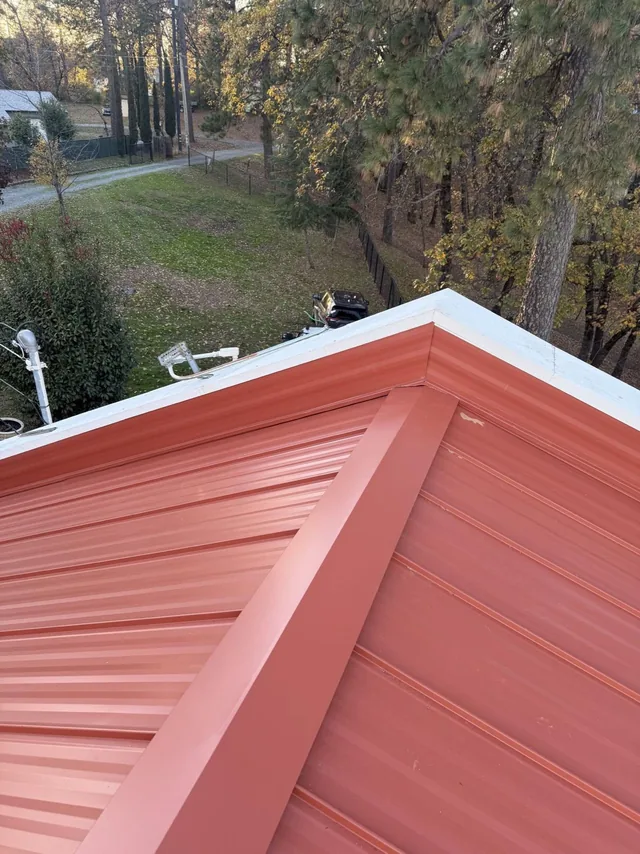 Clean ridge cap and trim on a red standing seam metal roof