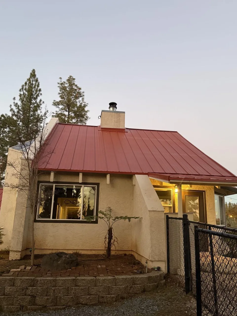 Red standing seam metal roof on a home with a chimney