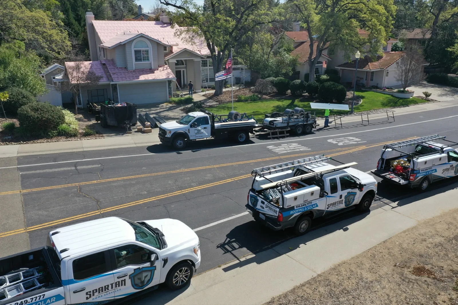 Spartan Home Services trucks at a roofing job